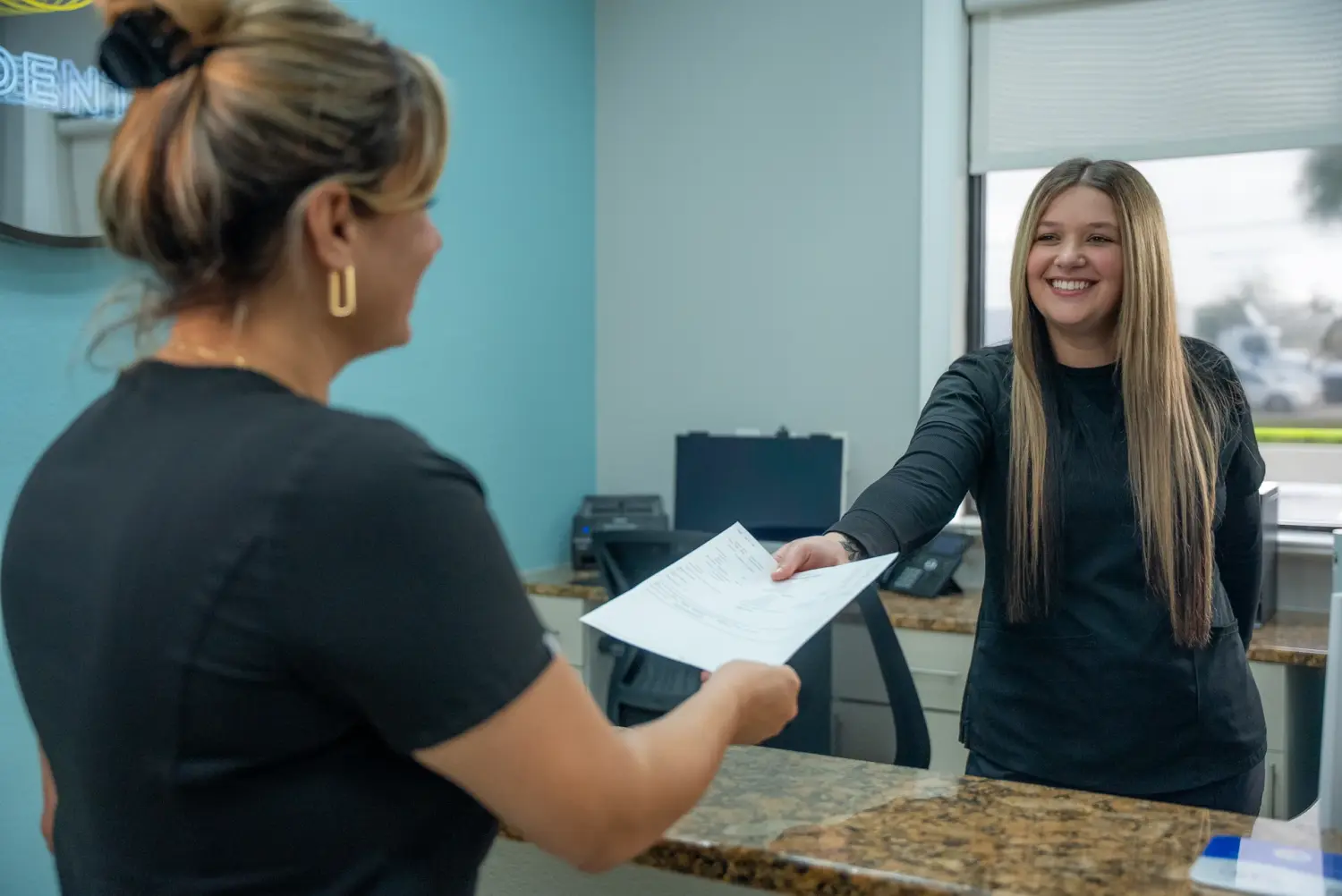 EZ Dental receptionist assisting patient with check-in forms in Fort Myers, FL